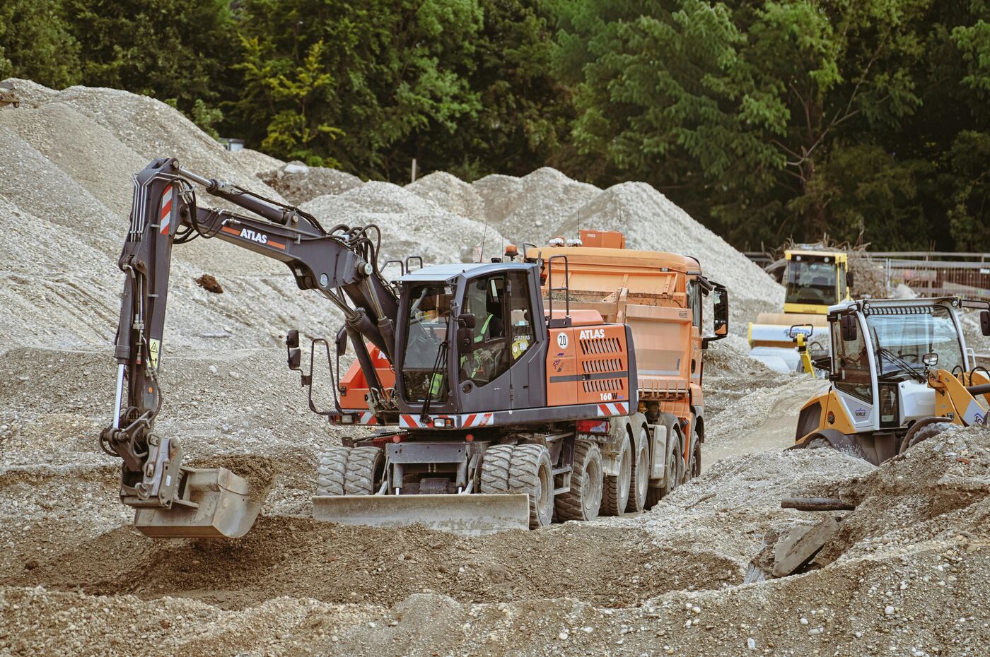 Wheeled excavator and dump truck working on aggregates yard